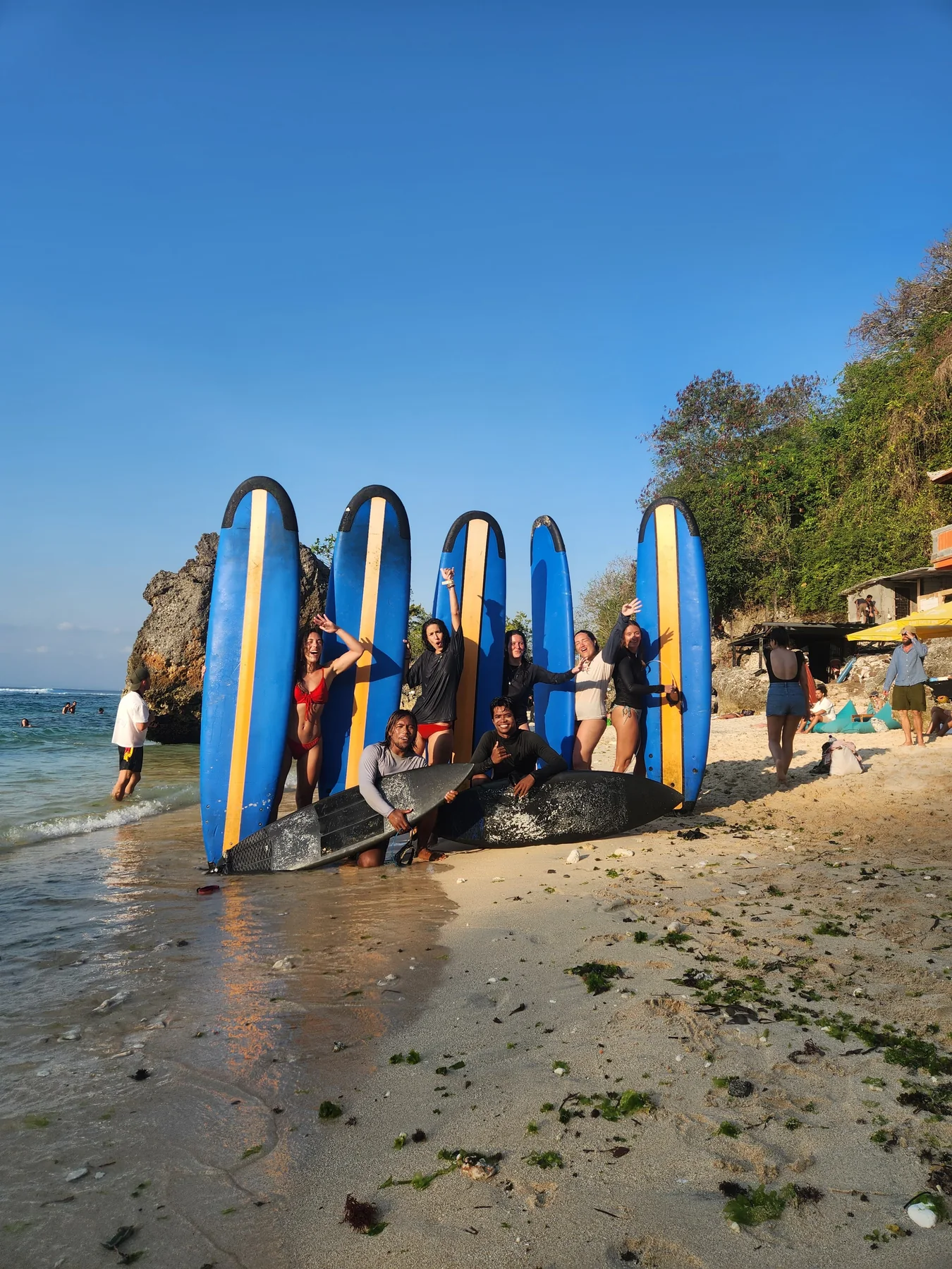 Papan surfing biru berjajar di pantai di bawah langit cerah